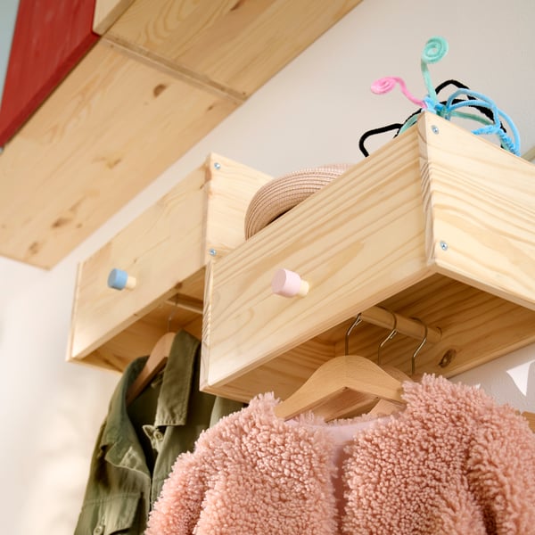 Close-up of RAGGBERG coat rack to show children’s jackets hanging below and some accessories sticking out from top shelf.