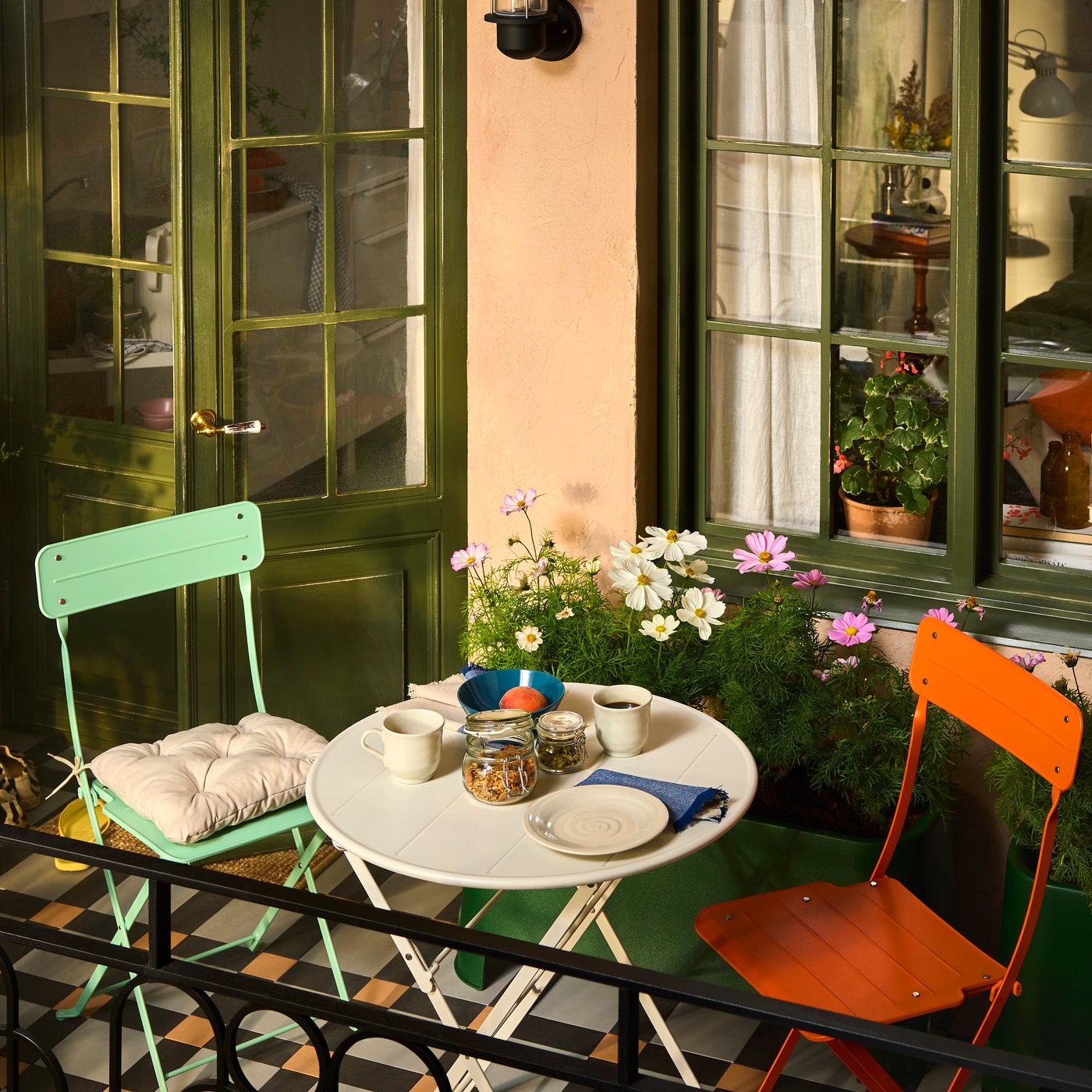 Un balcó amb mobiliari d'exterior SUNDSÖ de colors alegres, envoltat de plantes i dos armaris SUNDSÖ.