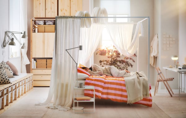 A modern bedroom with a bed, colorful pillows, and a person slepping. 