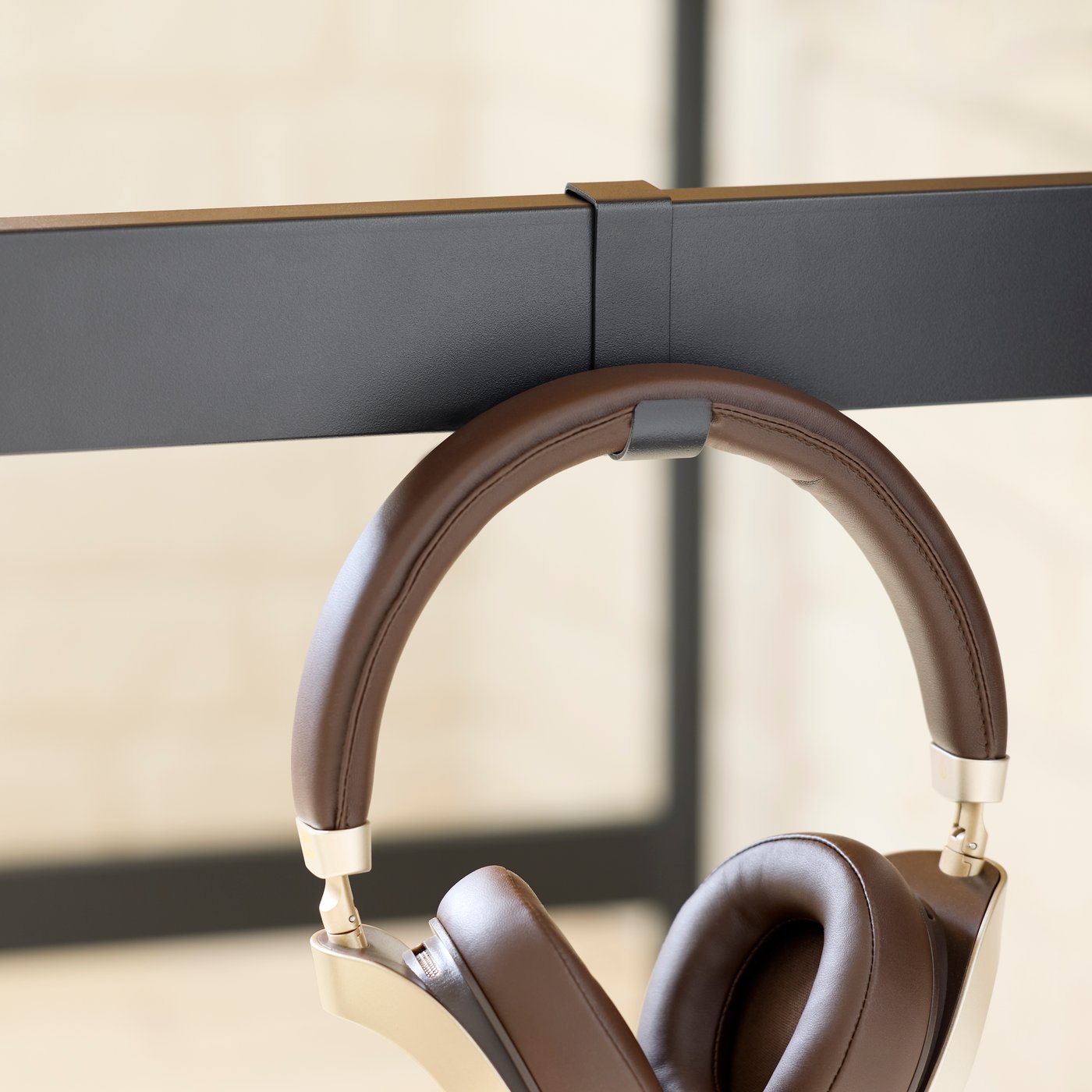 A close-up of the hook on the side of a MULLSJÖ desk, with a pair of headphones hanging on it.