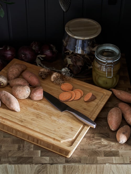 Bucătărie cu blat de lucru, bloc de măcelărie din lemn, borcan cu capac de sticlă, borcan cu capac, cuțit de bucătărie, legume și ingrediente.
