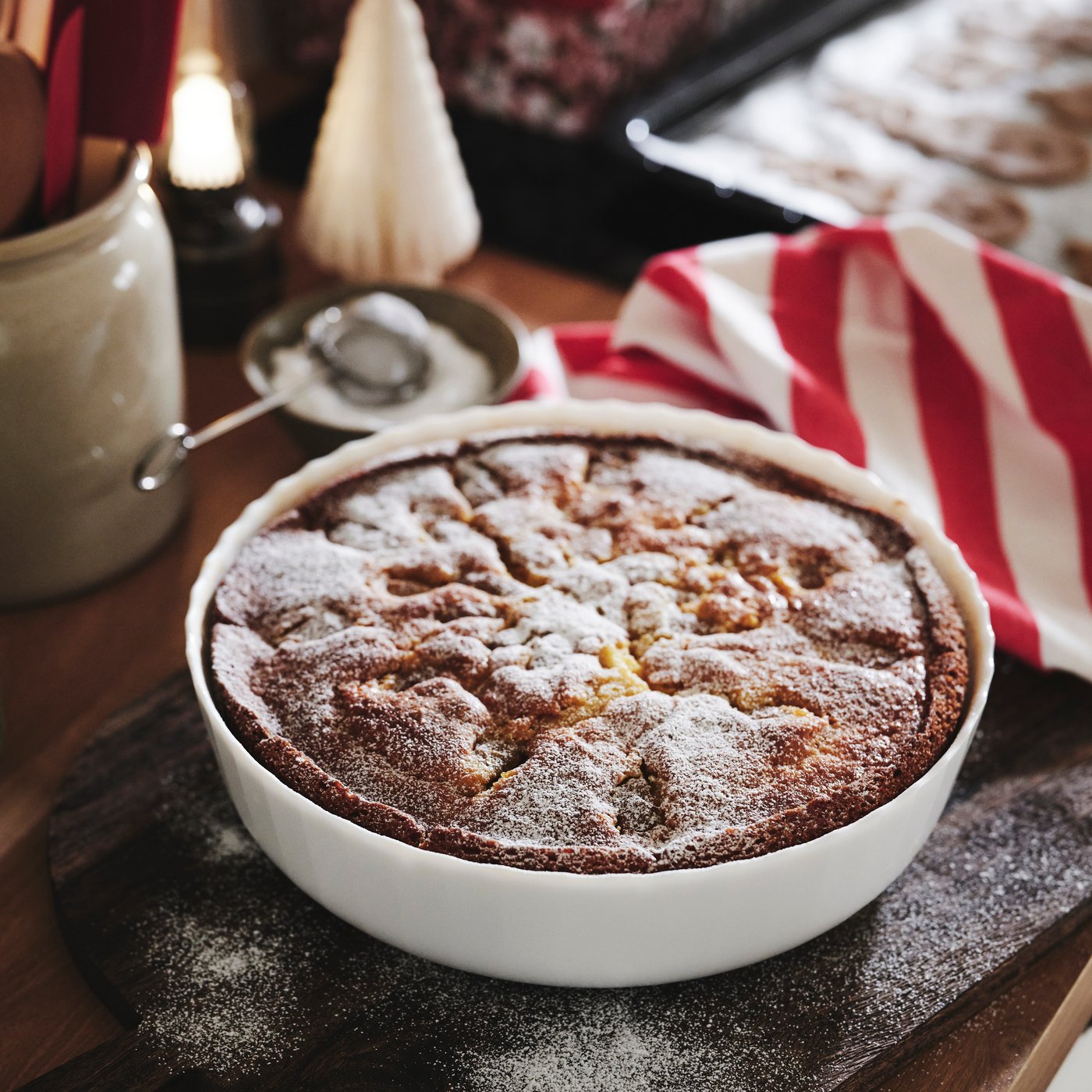 A white FISKTÄRNA oven dish filled with a freshly baked cake dusted with icing sugar.