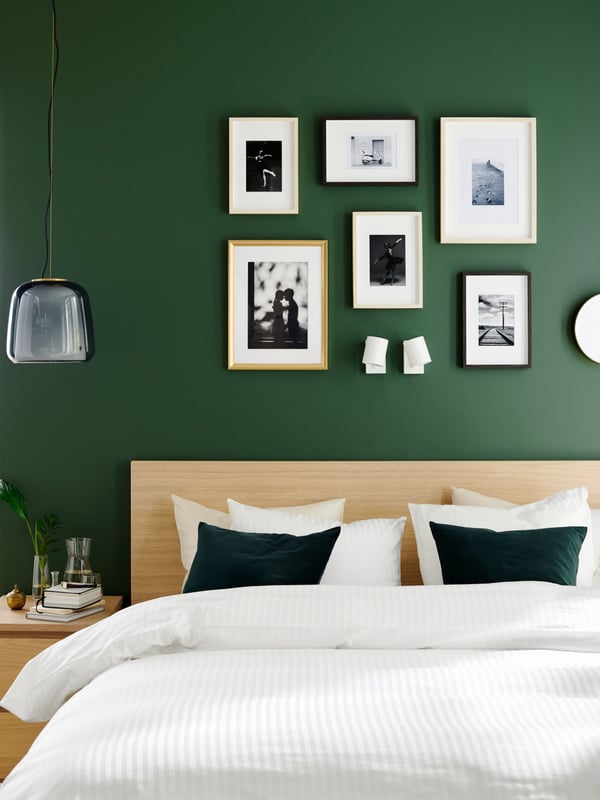 Decoració d'habitació amb marcs sobre una paret de color verd fosc