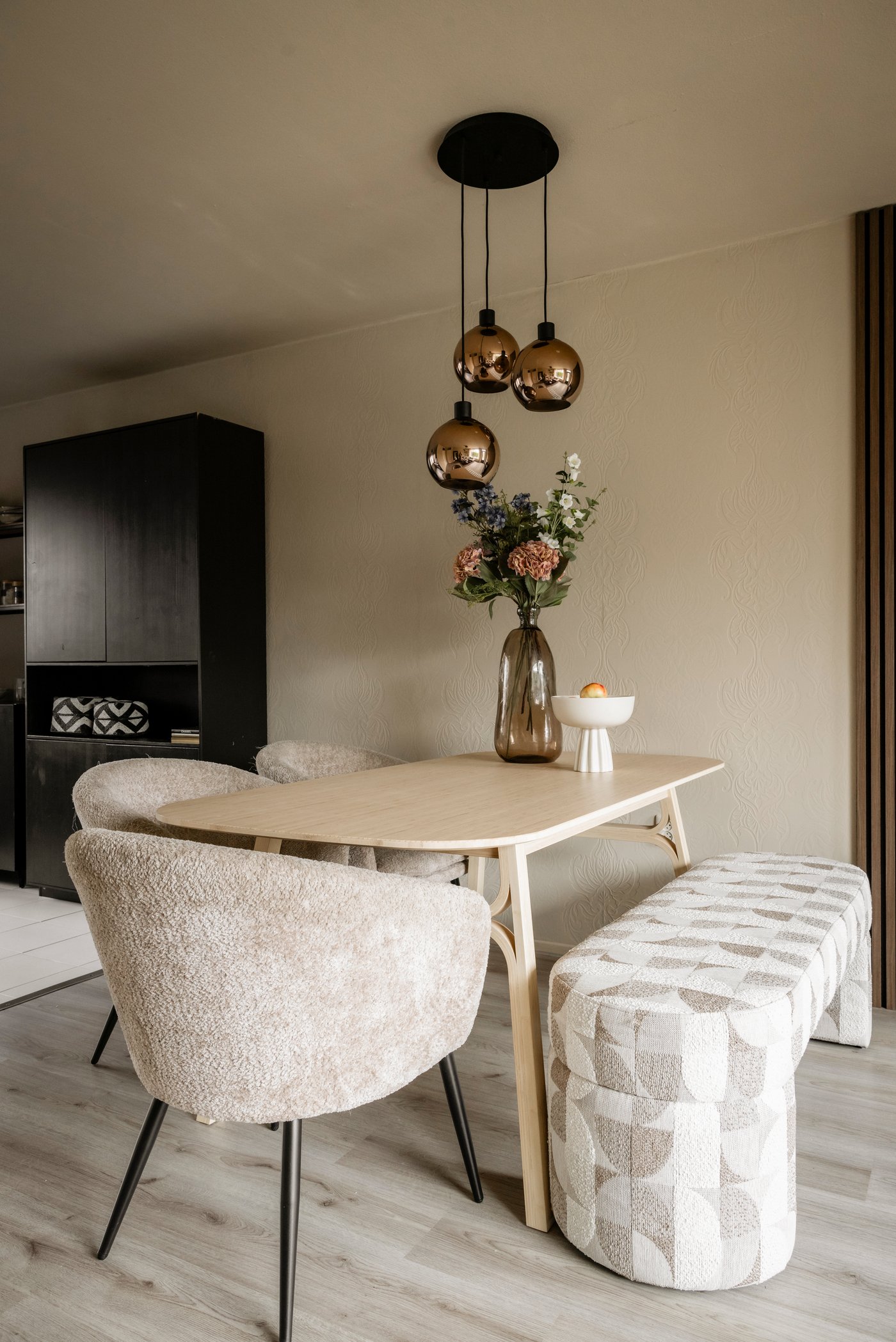 Eetkamerhoek in de woonkamer, met VOXLÖV eettafel en drie kuipstoeltjes en één bankje.