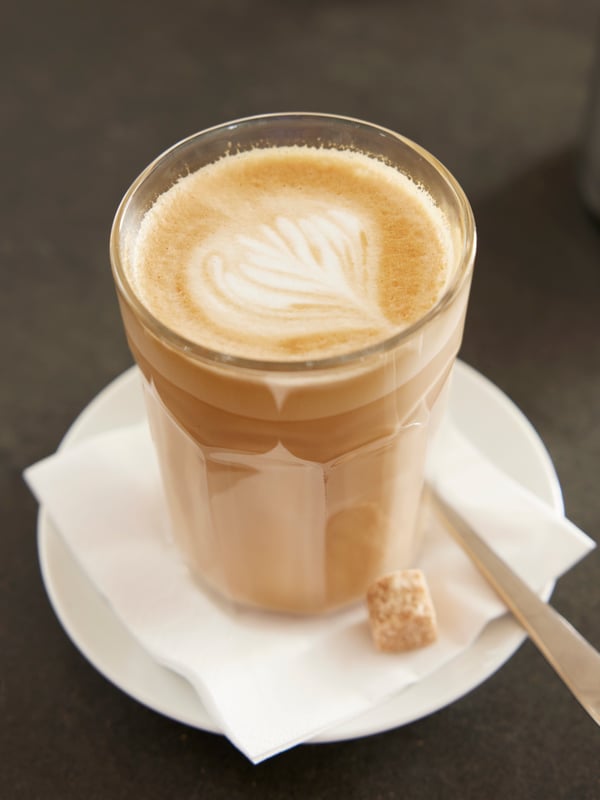 Ein POKAL Glas gefüllt mit Kaffe von oben. Auf der Untertasse ein langer DRAGON Löffel