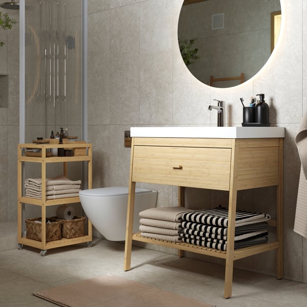 Un mueble abierto RÅGRUND / BACKSJÖN con lavabo y cajón, bambú, en un baño moderno y minimalista