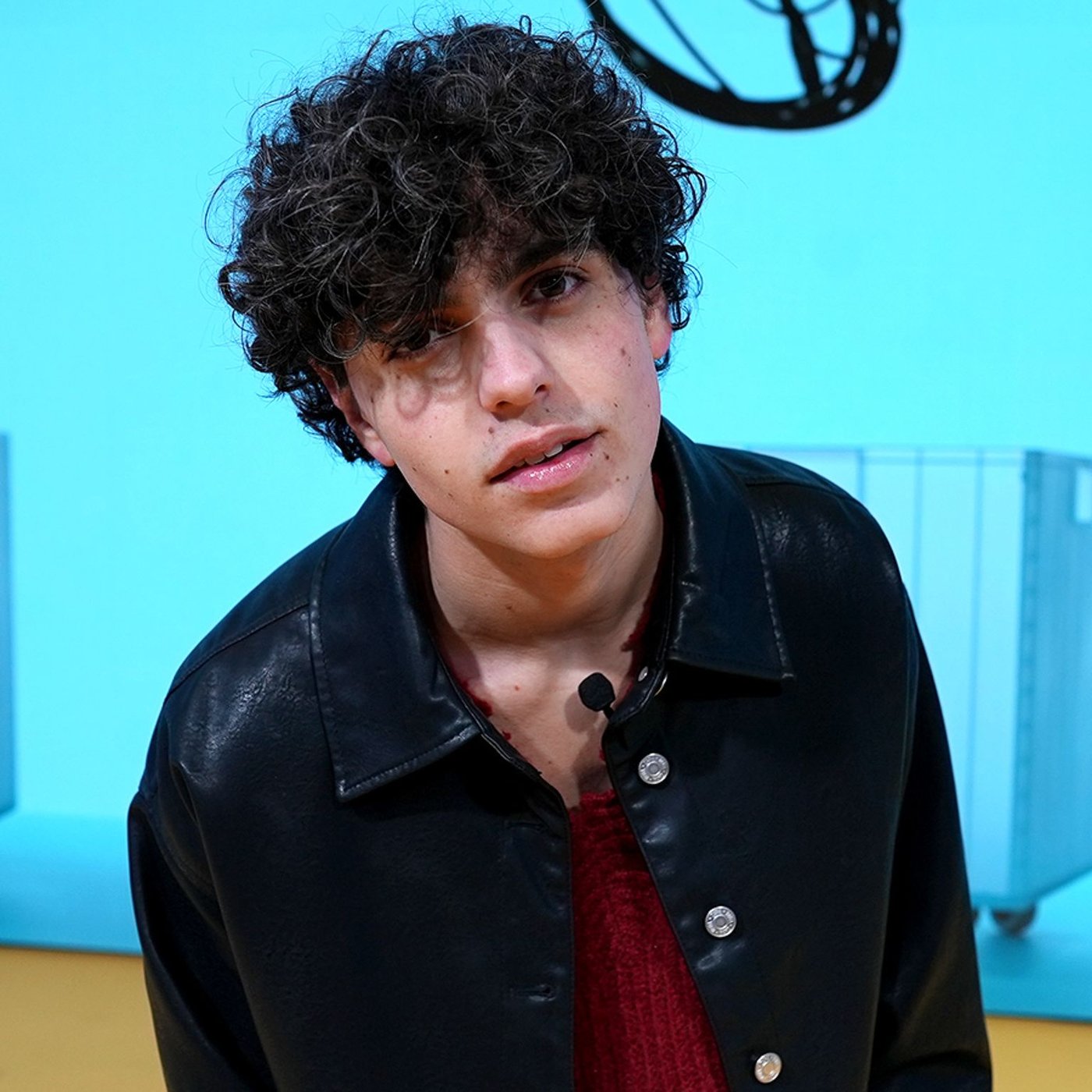 Während der Mailänder Designwoche 2024 steht Niveo am IKEA Standort auf einer Bühne. Er trägt ein schwarzes Hemd und eine Halskette. Im Hintergrund ist eine digitale Anzeige mit blauen IKEA Produkten zu sehen.