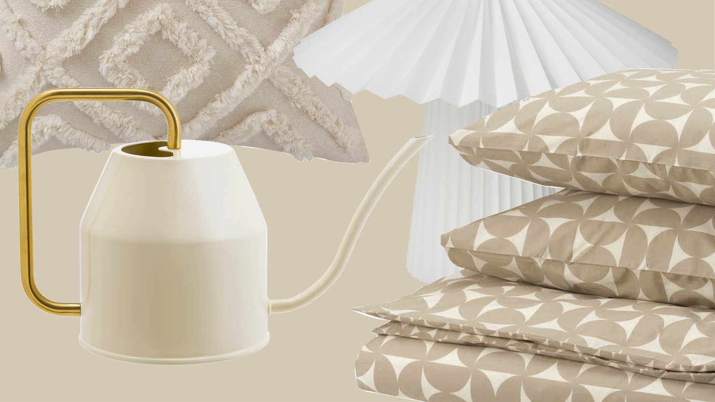 Een beige kussen met textuur, geometrisch IKEA-beddengoed, een witte geplooide lamp en een crèmekleurige gieter met een gouden handvat zorgen samen voor een rustige en stijlvolle slaapkamer.