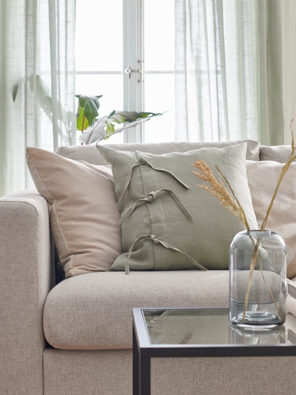 Beige and light green cushion in a beige VIMLE sofa in front of a table.