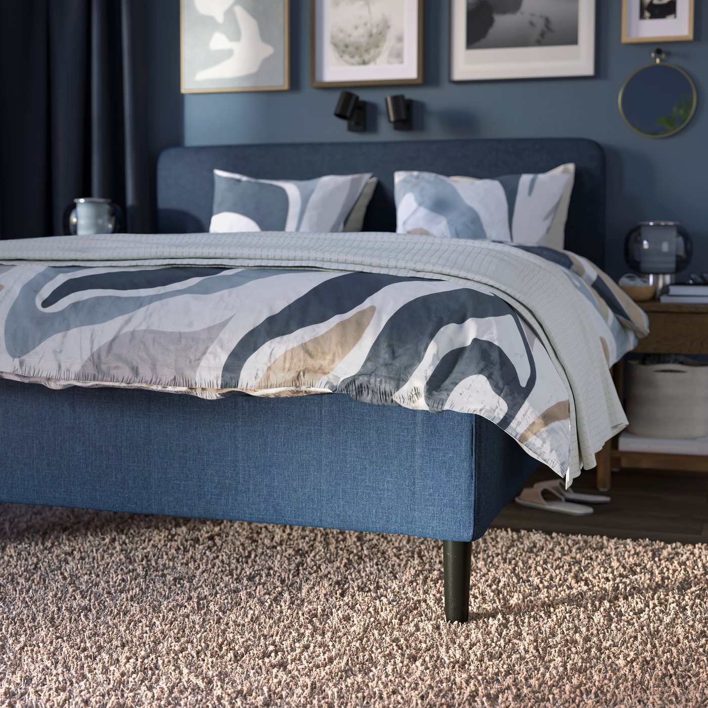 En mörkblå RISHÖJDEN resårmadrassbotten med 7 zoner, tillsammans med MYGGLASVINGE sängkläder i ett sovrum på en VOLLERSLEV matta.
