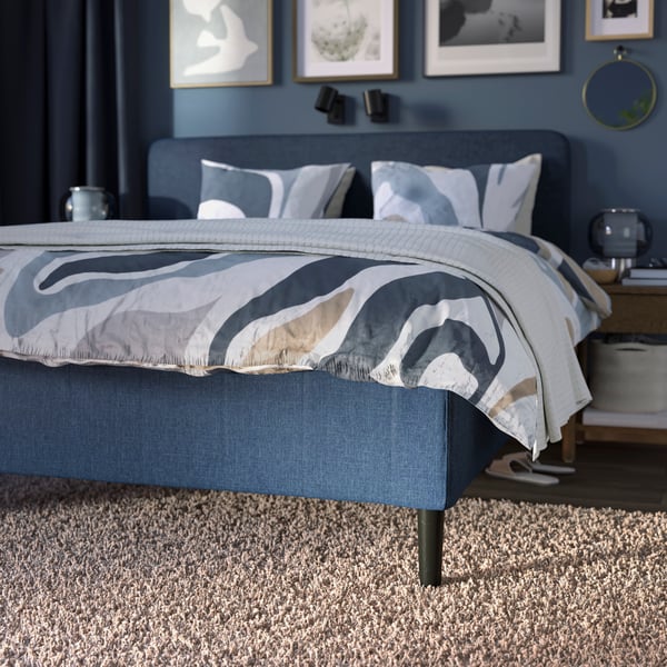 En mörkblå RISHÖJDEN resårmadrassbas med 7 zoner, med MYGGLASVINGE sängkläder i ett sovrum på en VOLLERSLEV matta.
