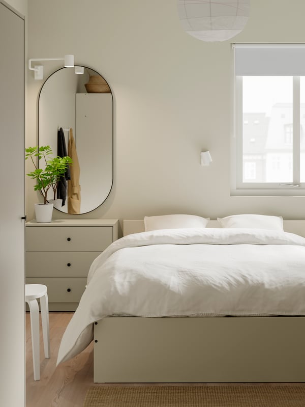 Beige byrå står bakom en beige säng.