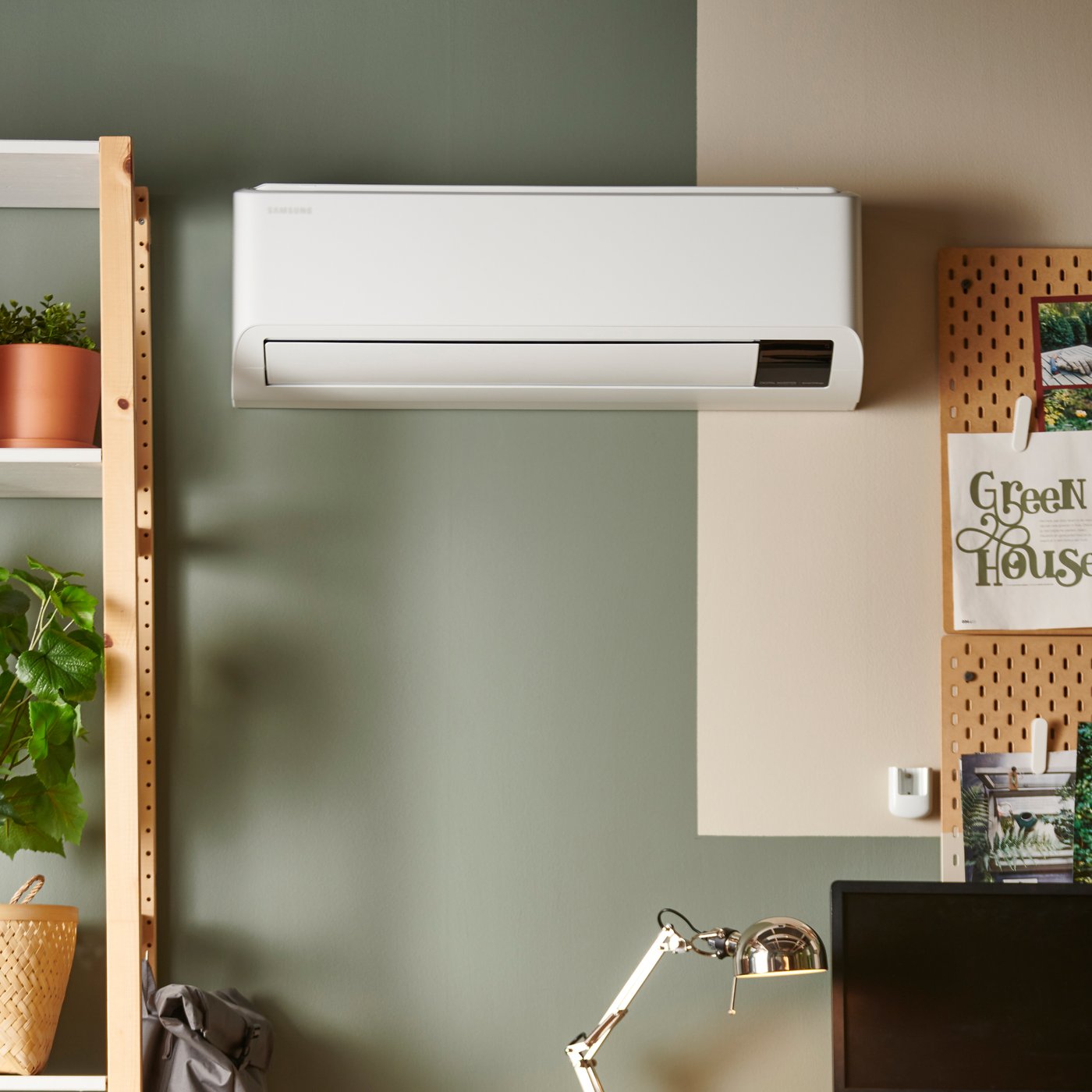A white air conditioning unit installed on a green-painted wall.