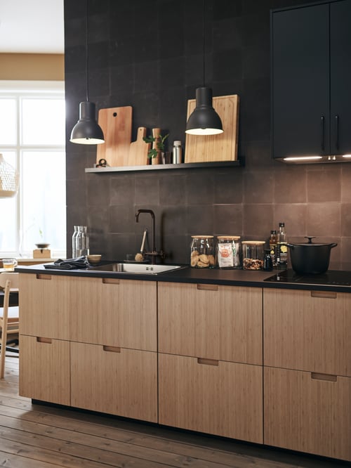 Small kitchen with base cabinets with space for sink, 2 natural wood fronts, 2 large drawers, sink, tap, black pendant lamps.