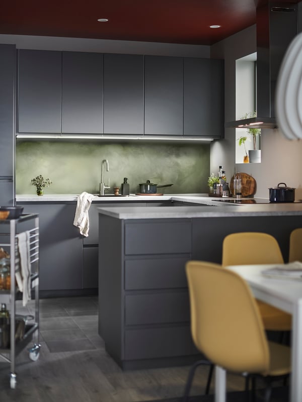Cuisine design grise en fond, avec des chaises jaunes autour de la table