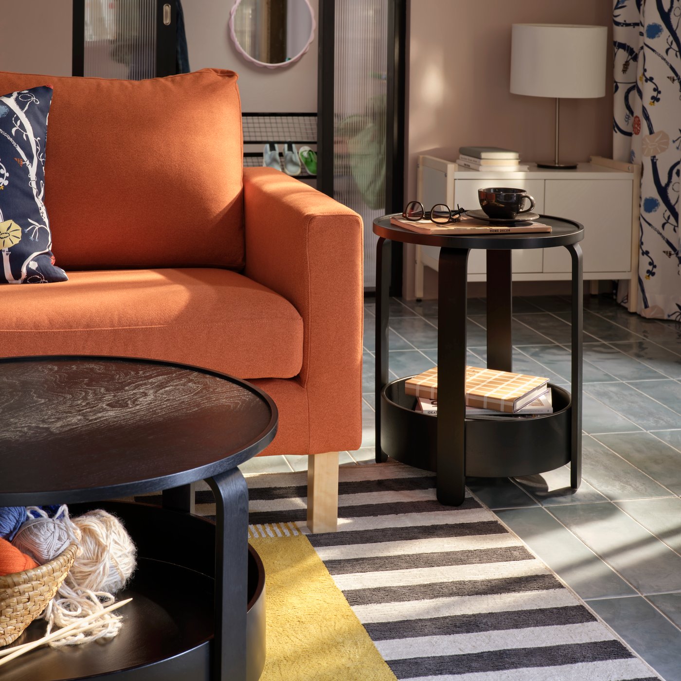 A light living room with a black BORGEBY side table and coffee table, both placed near a red-brown SALTSJÖBADEN sofa.