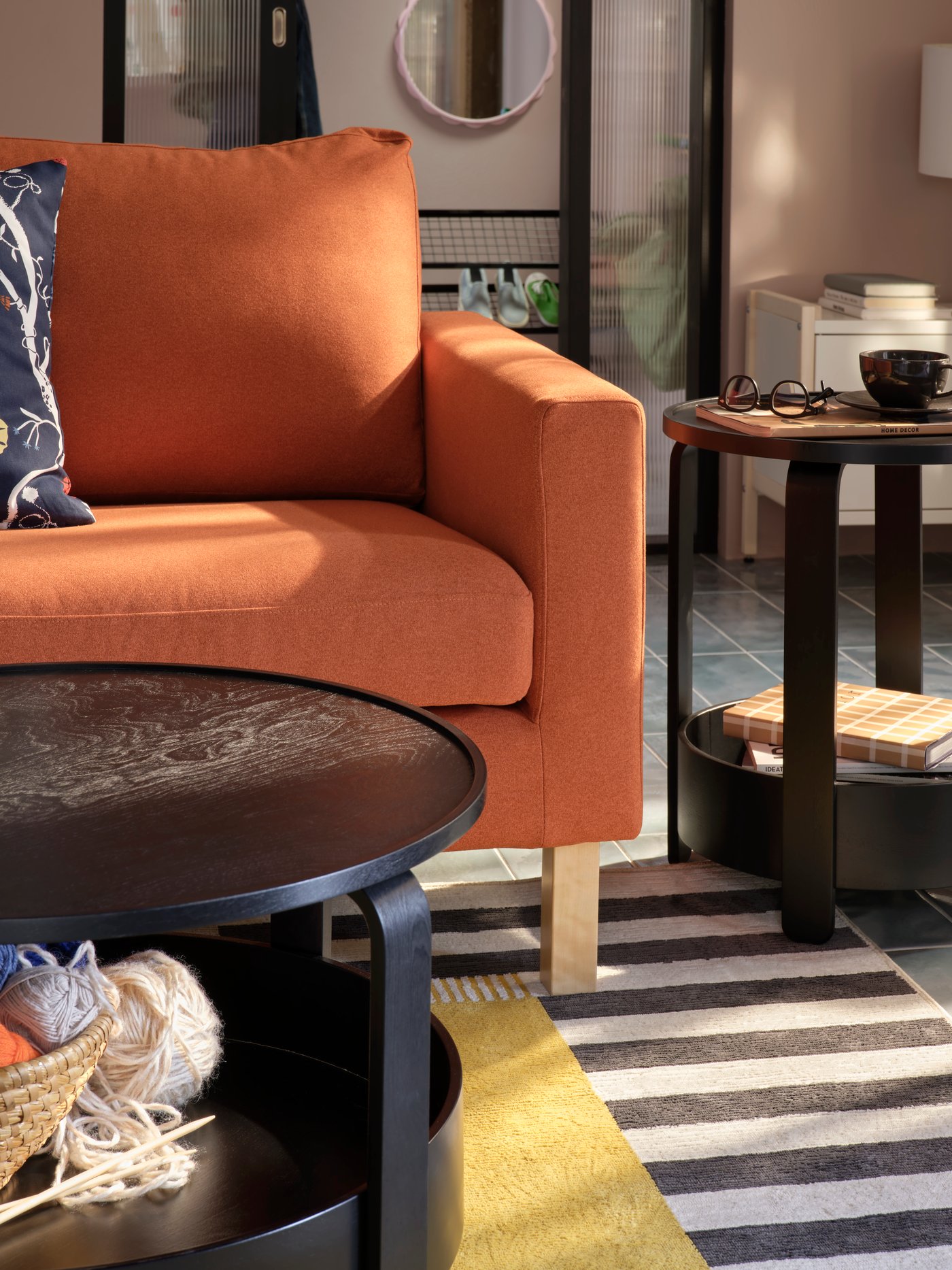 Een lichte woonkamer met een zwarte BORGEBY bijzettafel en salontafel, beide geplaatst naast een roodbruine SALTSJÖBADEN bank.