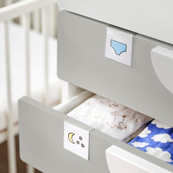 HÄNGIG label holders with pictures are attached to two drawers in a SMÅSTAD wardrobe. The lower drawer is open.