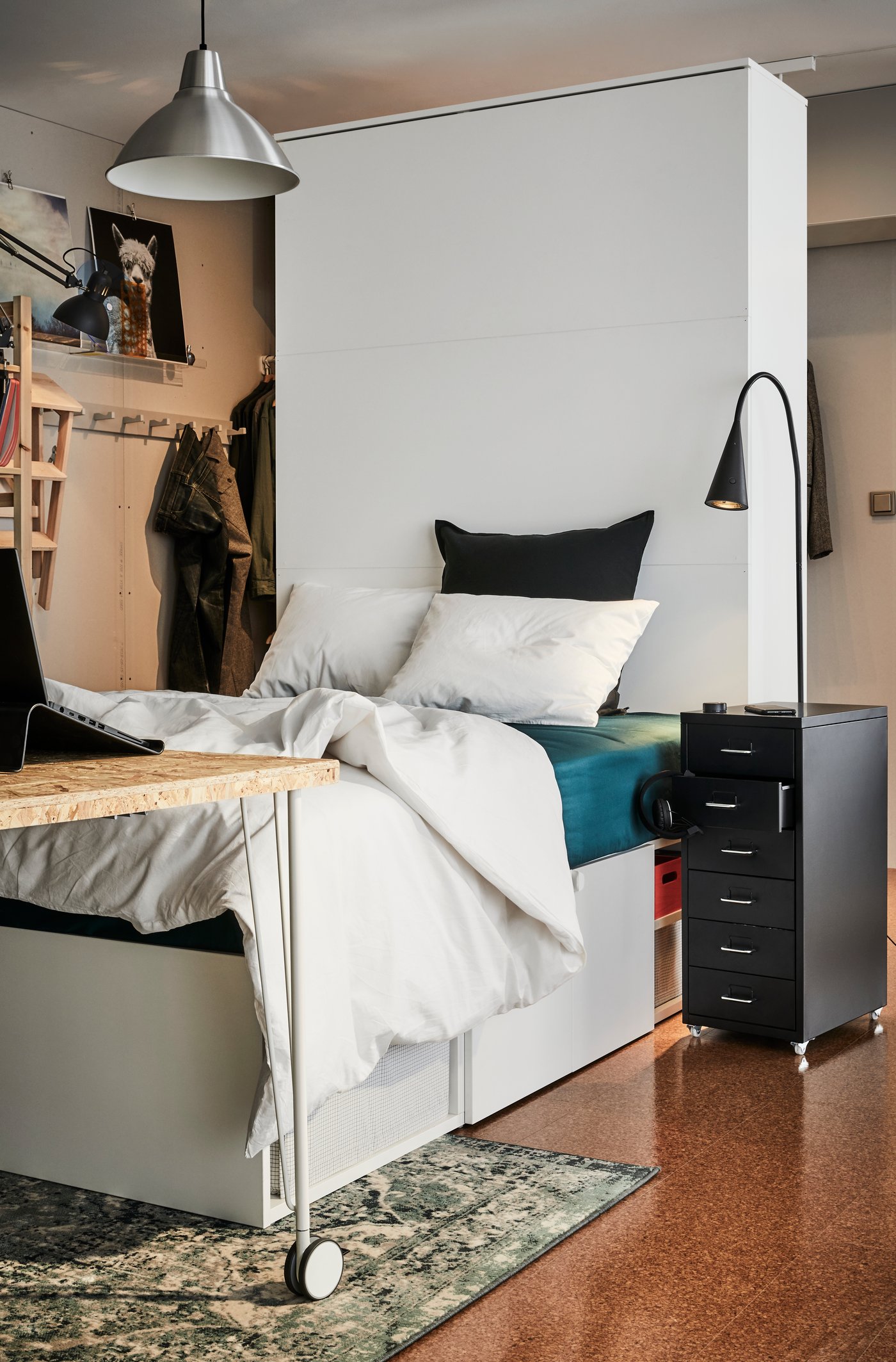 A white SLÄKT bed frame with storage in a shared flat room.