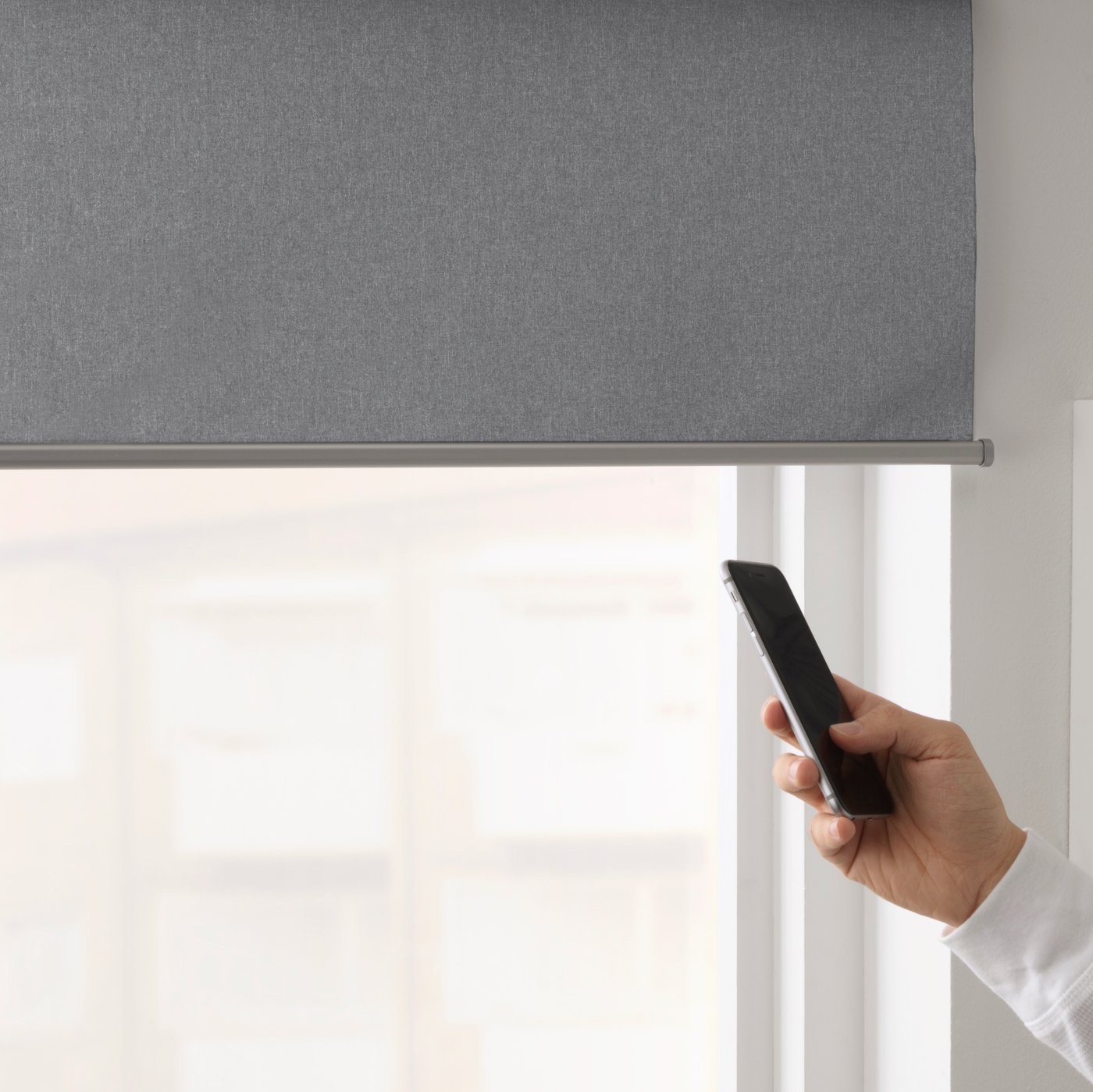 En fjärrkontroll i en hand som styr FYRTUR rullgardin.