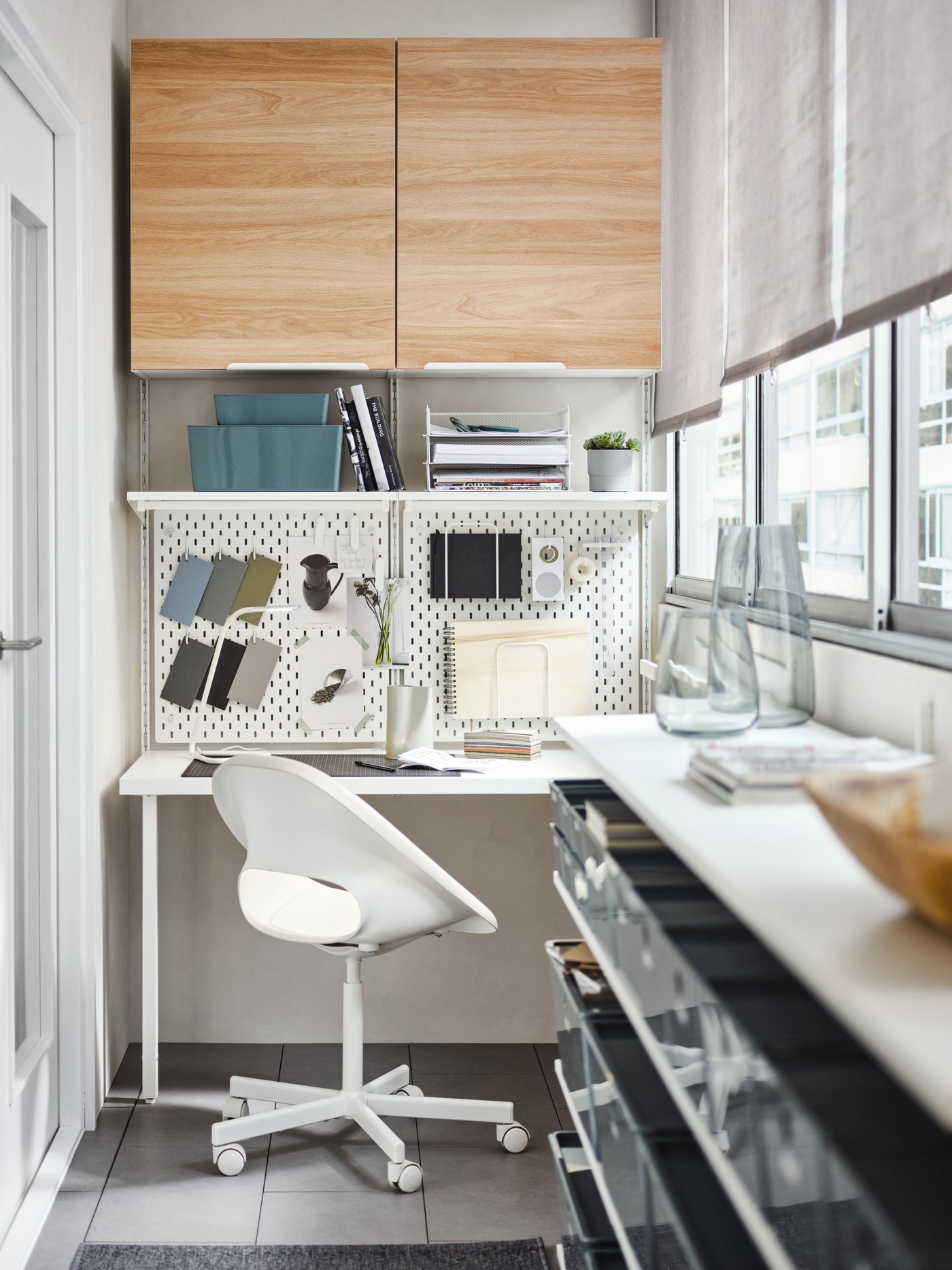 Espacio de trabajo moderno con dos armarios de pared de tablero de fibras en color beige con 2 estantes y 1 puerta encima de un estante blanco.