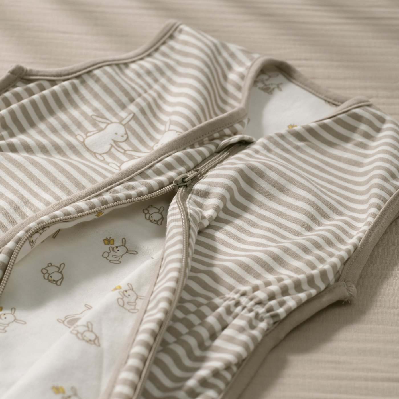 Du linge de lit IKEA plié, à fines rayures grises et blanches et orné de discrets motifs de feuilles, repose sur un fond clair.