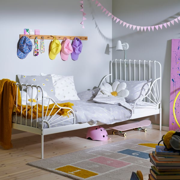 A white MINNEN extendable bed in a child’s bedroom with floral grey and white NATTSLÄNDA bed linen on top.