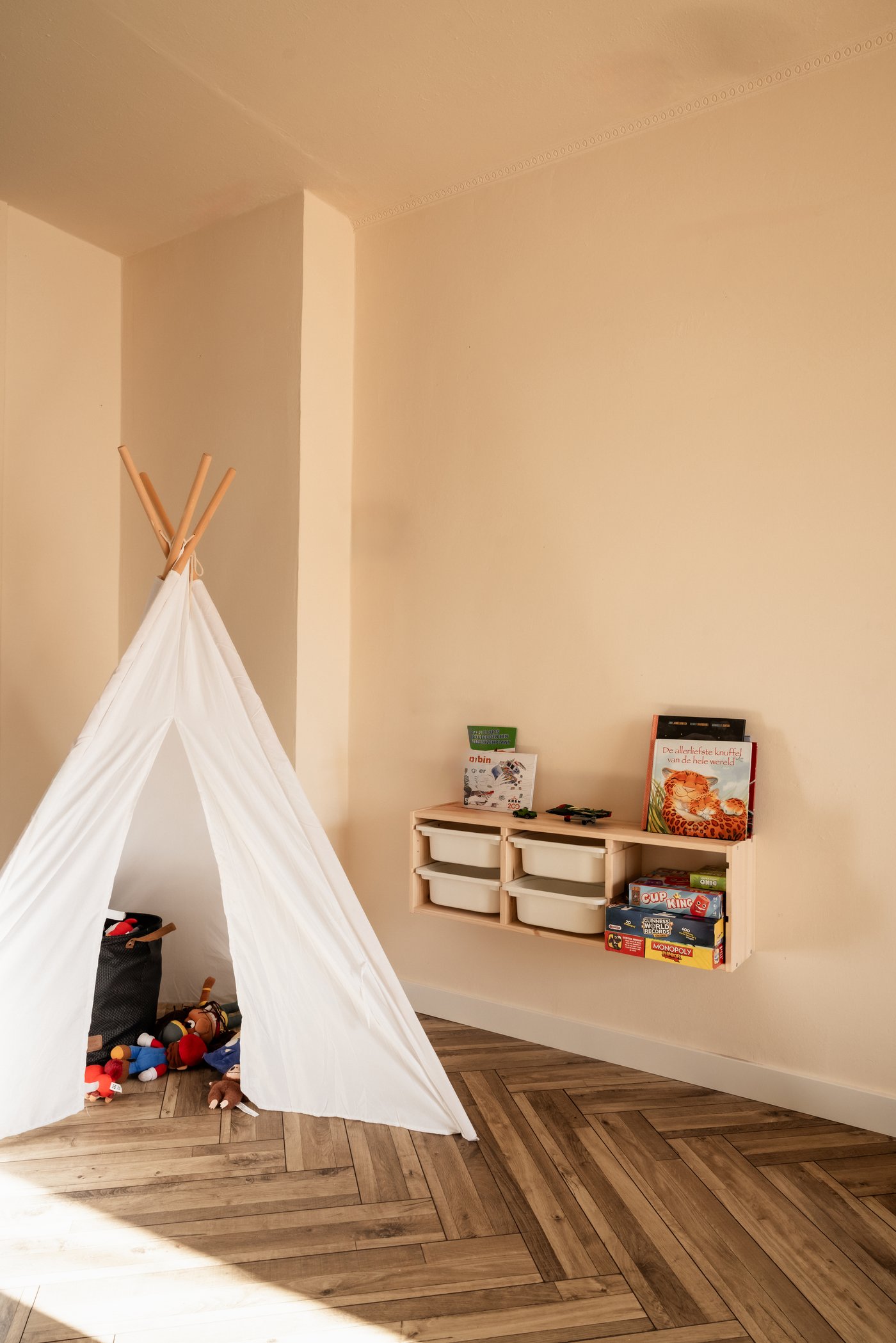 Kinderhoek in de woonkamer met witte tipi speeltent. Aan de muur hang een TROFAST opbergsysteem.