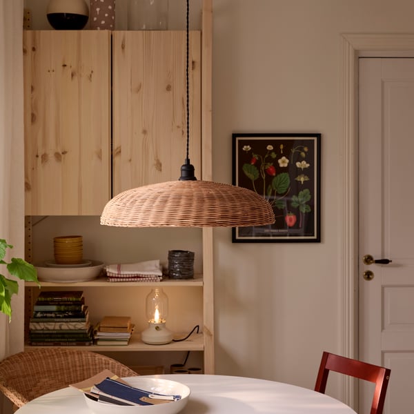 NARRKOLV pendant lamp in rattan hanging above a white ROSENTROP table with IVAR shelving unit behind it.
