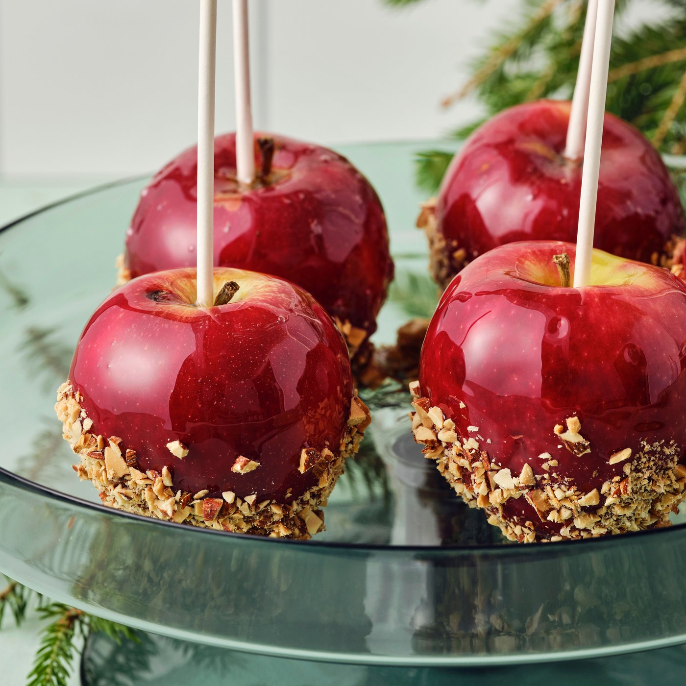Five candied apples on a green glass serving plate.