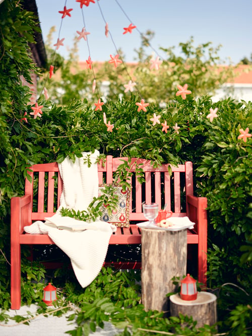 Take a break outside on a red PÄRONHOLMEN picnic bench, made comfy with a blanket and outdoor cushions.