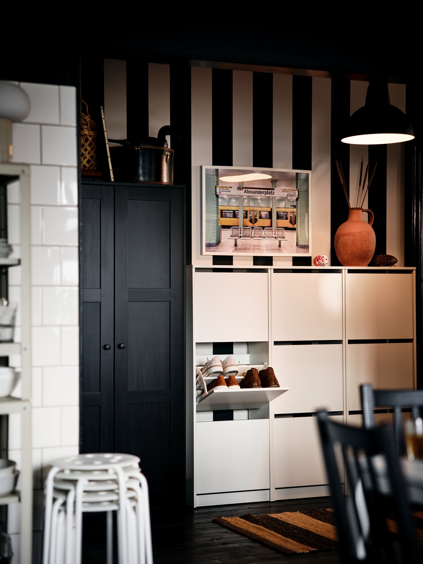 A section of a black-and-white-striped hallway with white BISSA shoe cabinets and a black-brown RAKKESTAD wardrobe.