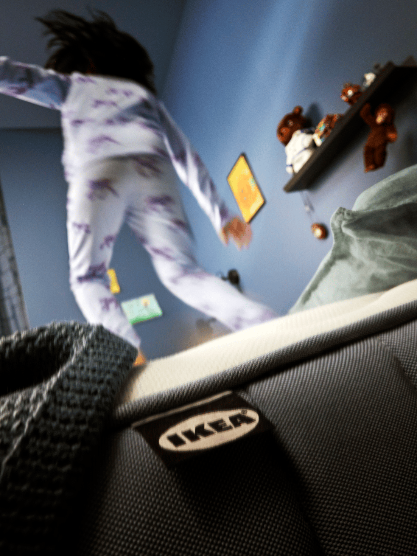 Un enfant se tient debout sur un matelas à ressorts ensachés VÅGSTRANDA bleu clair.