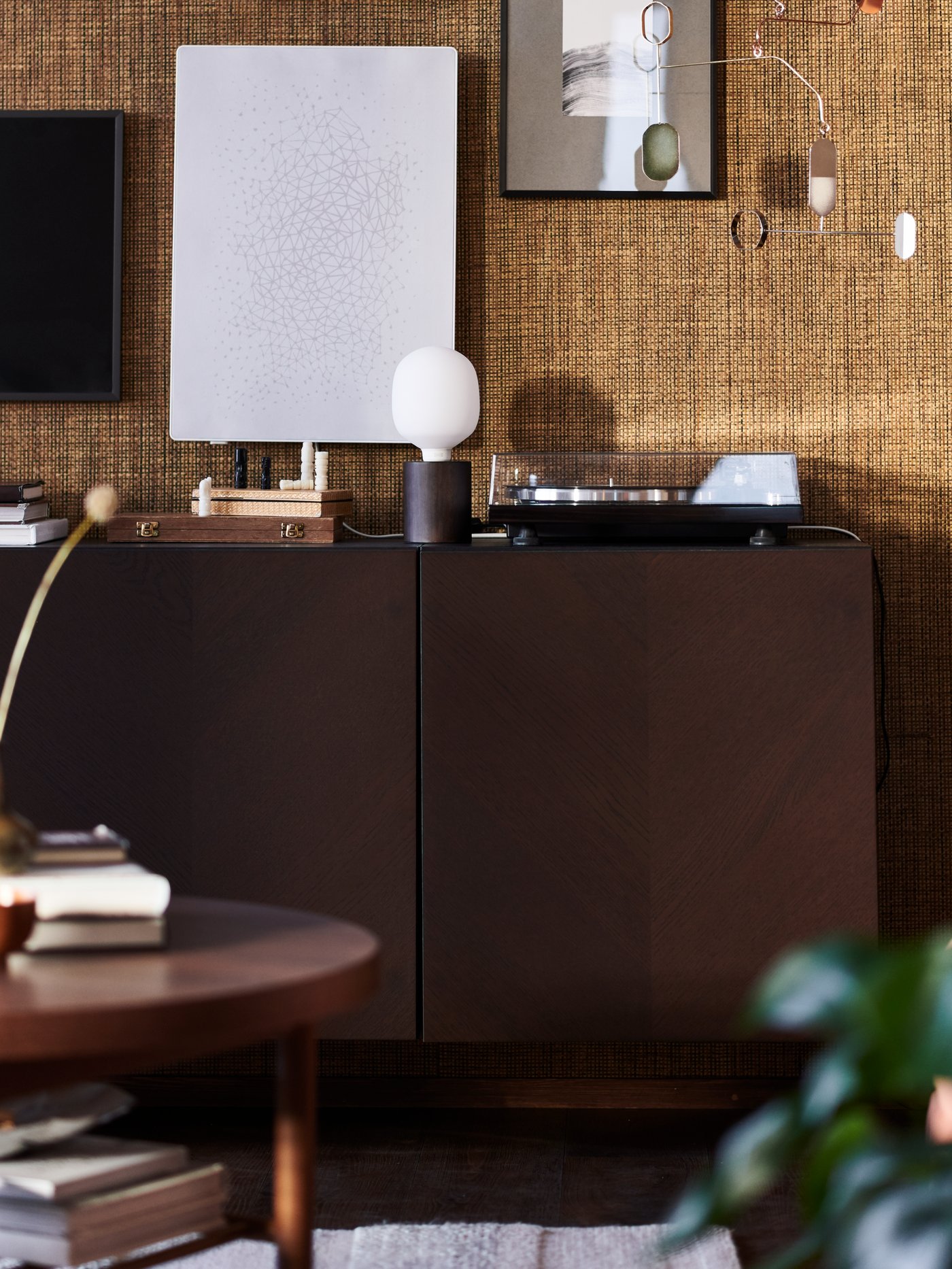 ארון BESTÅ בצבע חום כהה בחדר חום, שבו מנורת שולחן BLEKKLINT ומסגרת תמונה SYMFONISK עם רמקול WiFi.