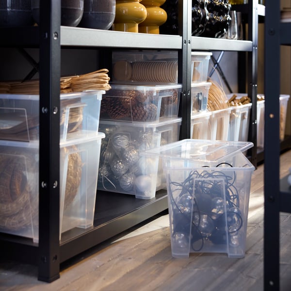 Transparent SAMLA boxes with lids are neatly stored on BROR shelves, containing various decor items.