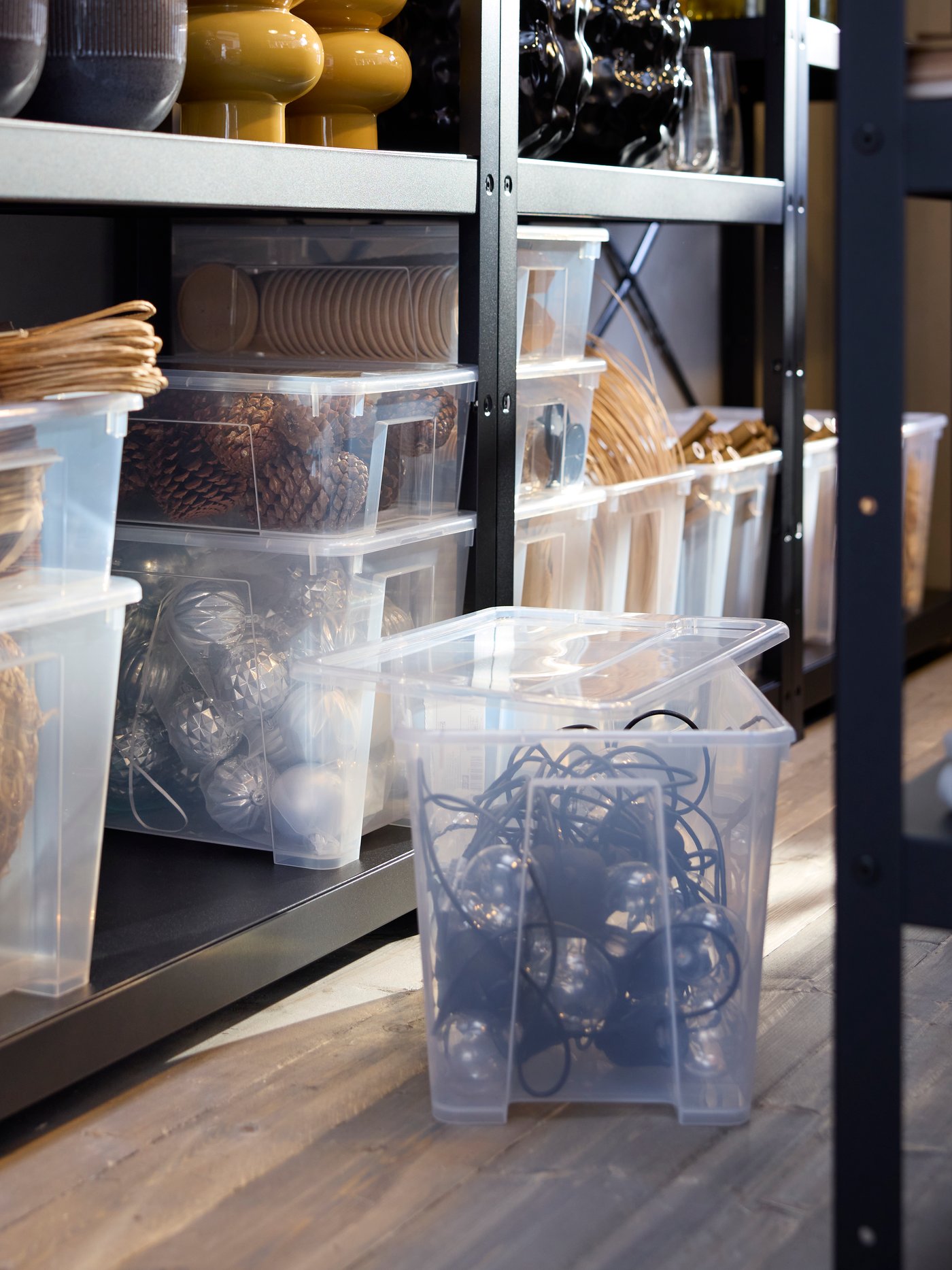 Transparente SAMLA Boxen mit Deckel werden ordentlich in BROR Regalen aufbewahrt und enthalten verschiedene Dekorationsartikel.