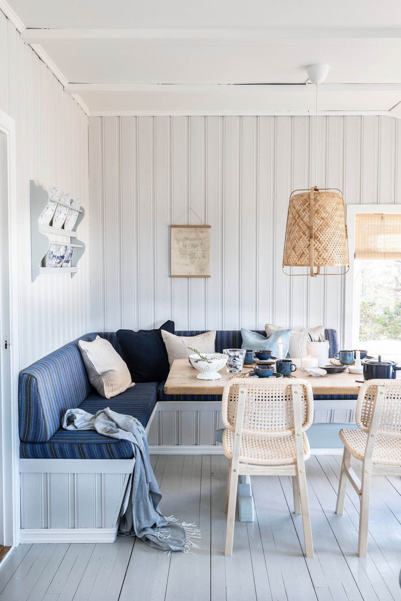 En spisekrog i et lyst sommerhus med trævægge.