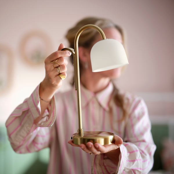 Een batterijgevoede TVÅMASTAD LED-lamp van messing/opaalwit glas