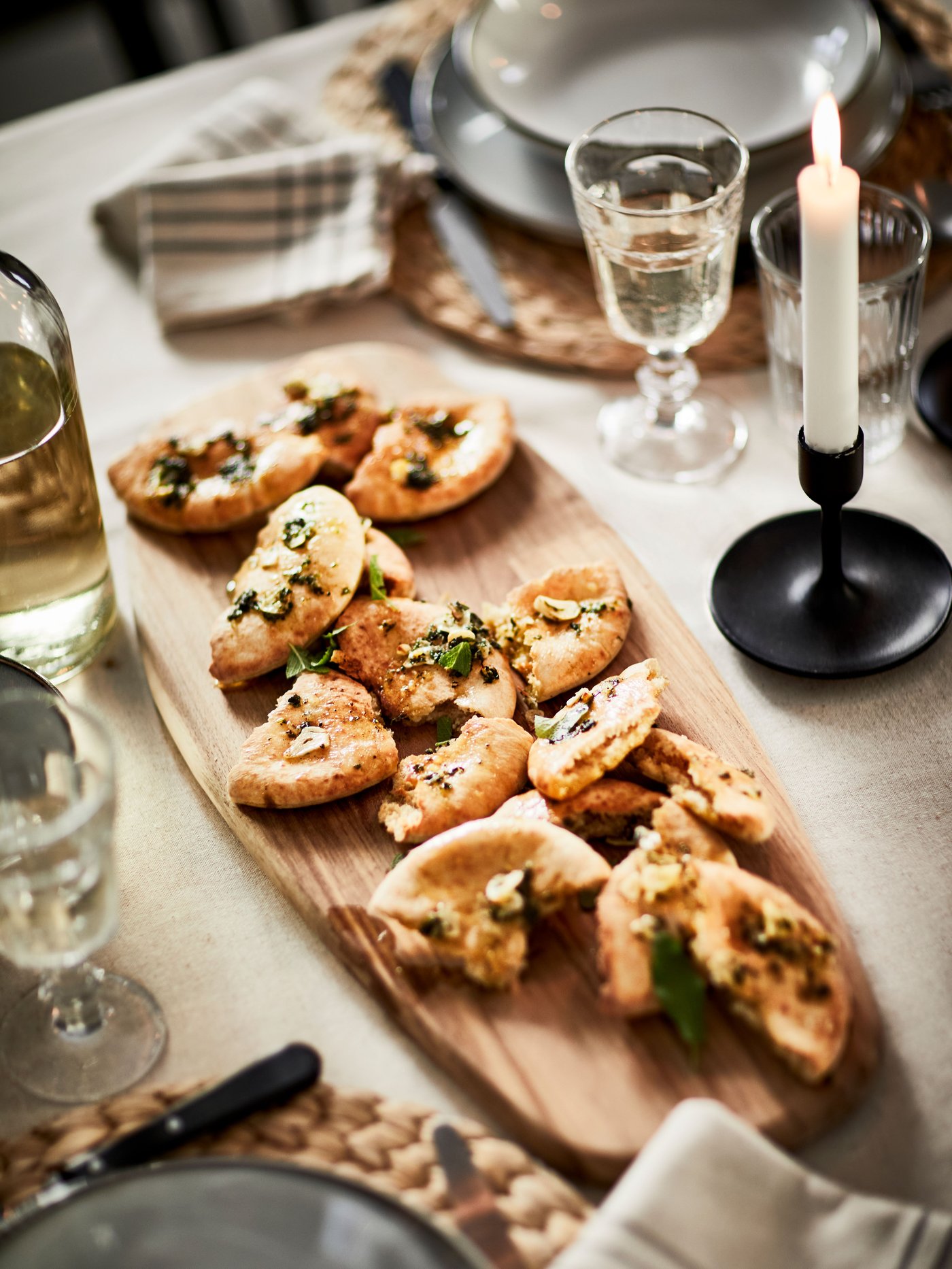 A snack board filled with delicious treats on a set dining table, accompanied by a black FULLTALIG candelabra.