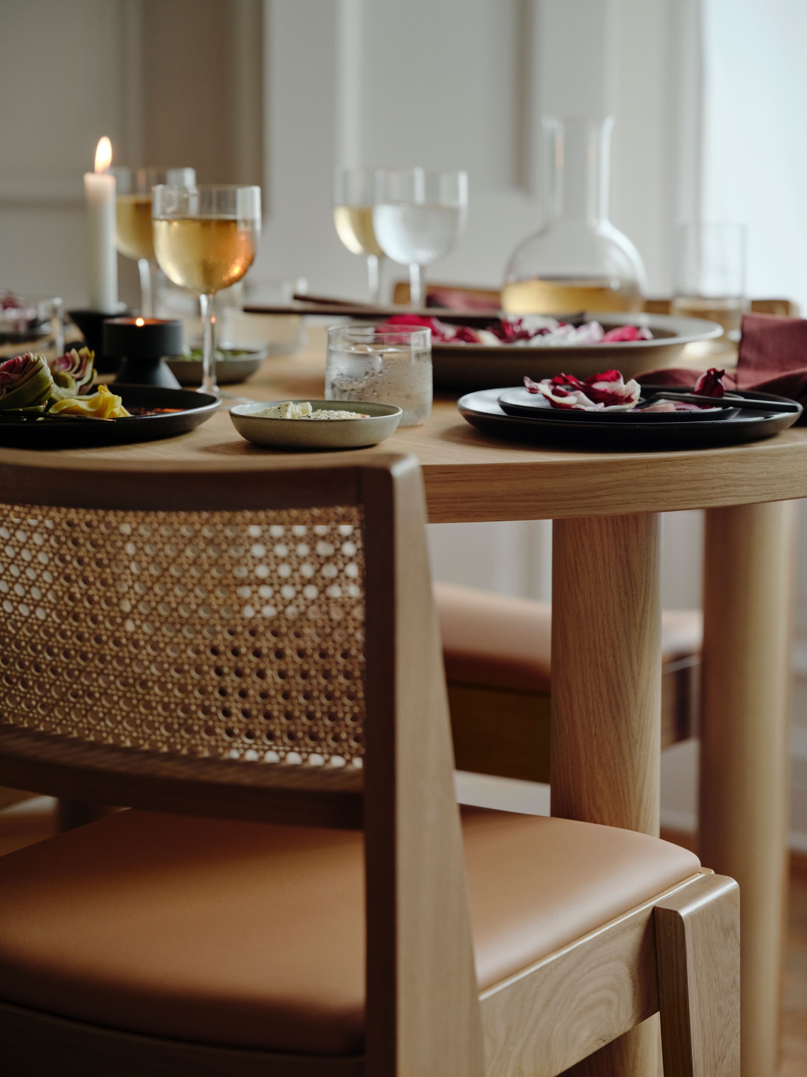 Xogo de mesa STOCKHOLM 2025 de chapa de carballo con pratos e fontes, copas de viño, unha xerra e unha candea acesa.