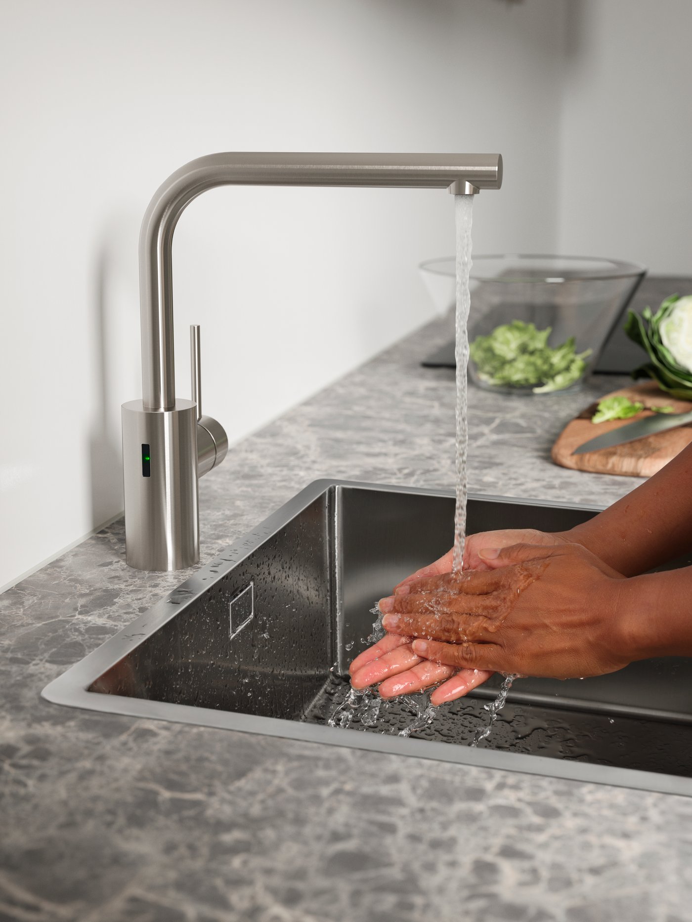 A man washes his hands with water from the TÄMNAREN automatic sensor water tap.