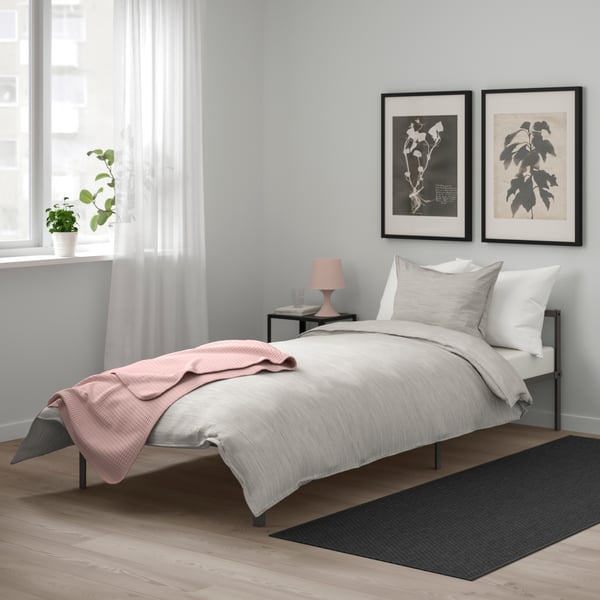 Una alfombra MORUM gris como bajada de cama en un dormitorio.