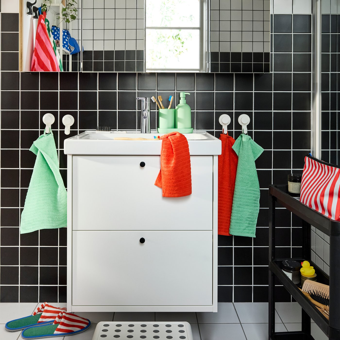 A white HAVBÄCK/ORRSJÖN vanity with two drawers and four mirror cabinets above it. Colourful towels on white hooks.