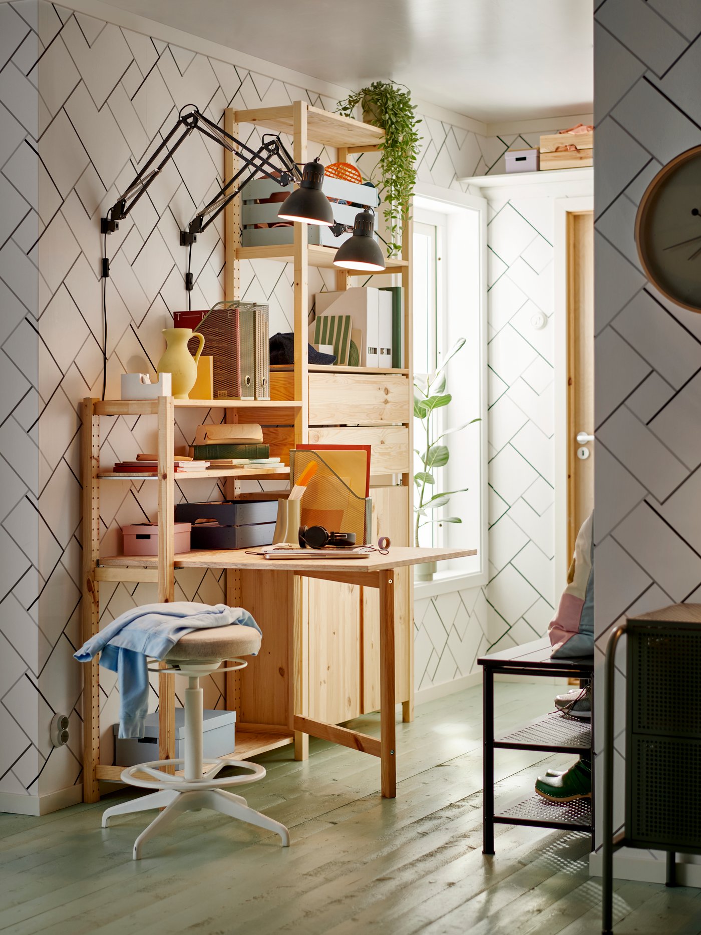 Several ivar shelves mounted on a wall with furnishings inside and a red stool in front.