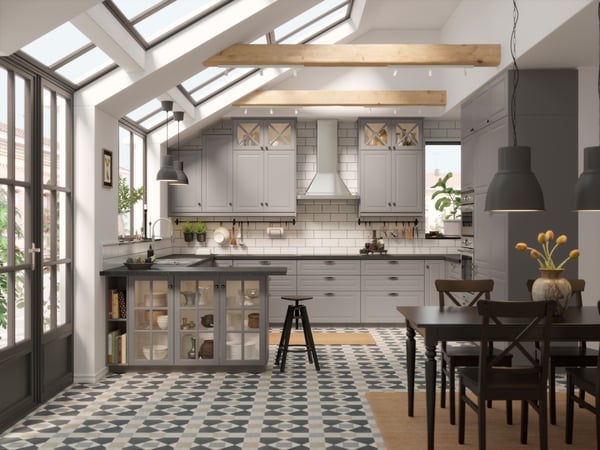 Fehér-szürke konyha terve egy tableten és a megvalósult konyha a háttérben.