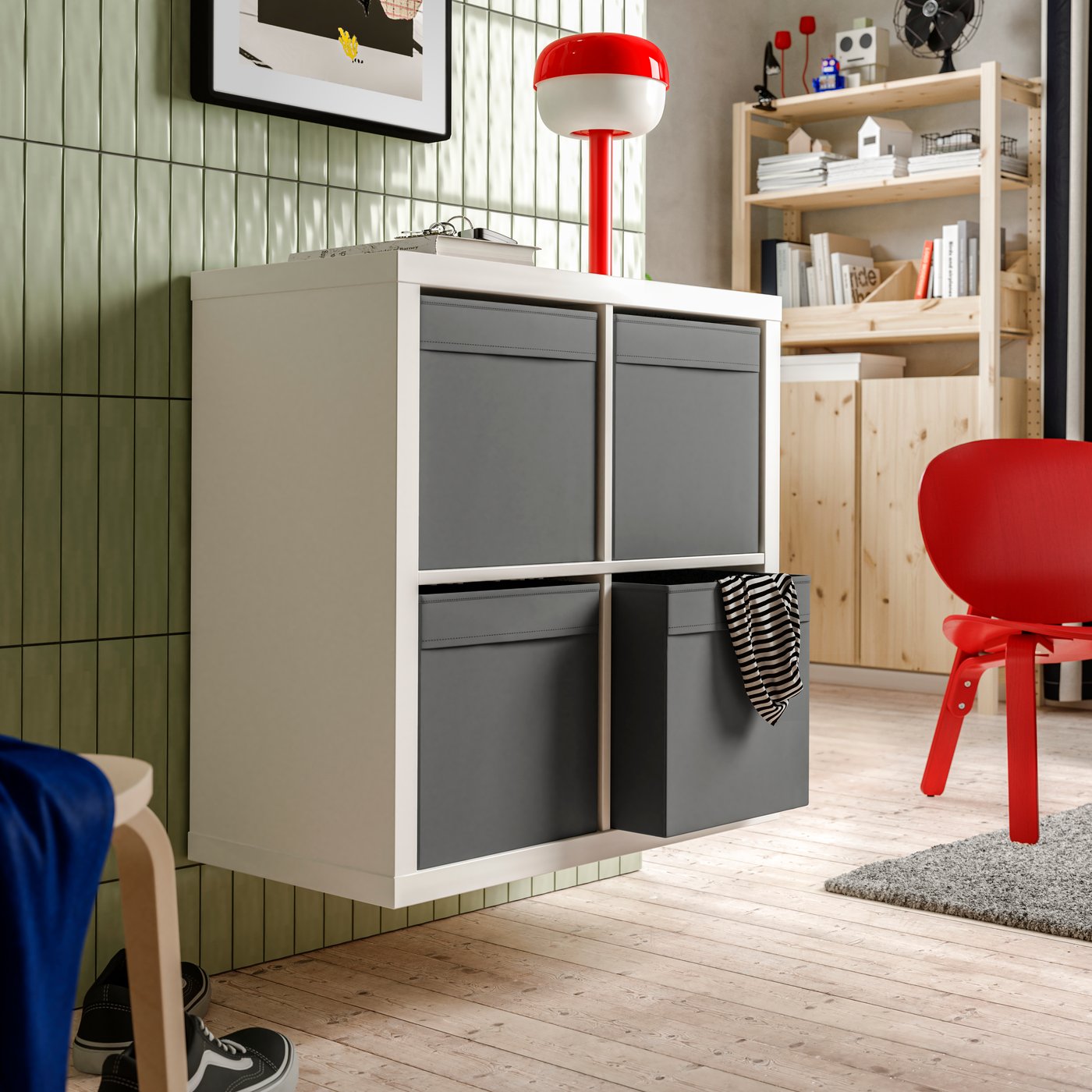 Una parete con una scaffalatura KALLAX bianca appesa al muro con un contenitore DRÖNA grigio scuro in ciascuno dei suoi quattro scomparti.