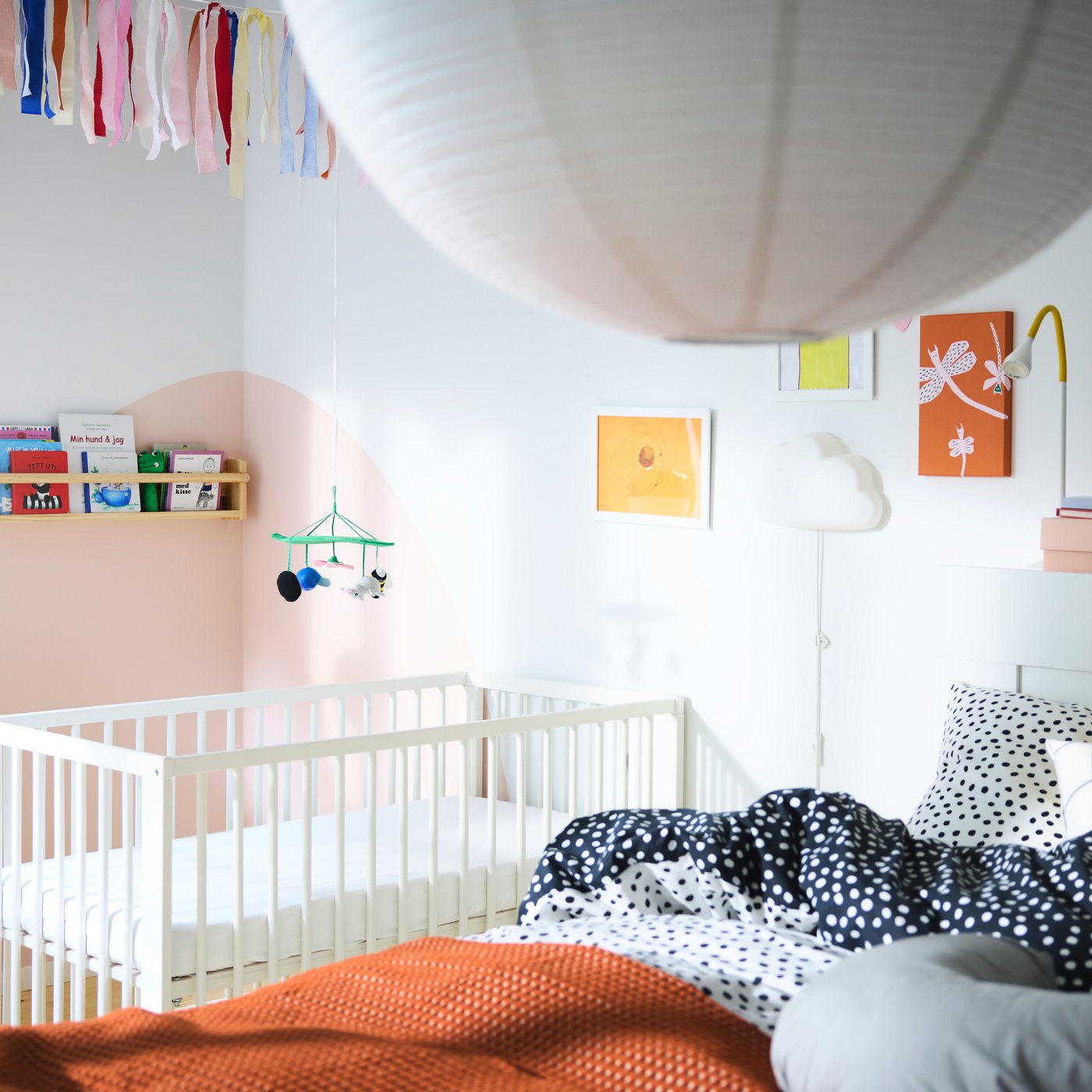 Una camera da letto con un grande letto in primo piano e un lettino sullo sfondo, diversi scaffali con libri e molti quadri.