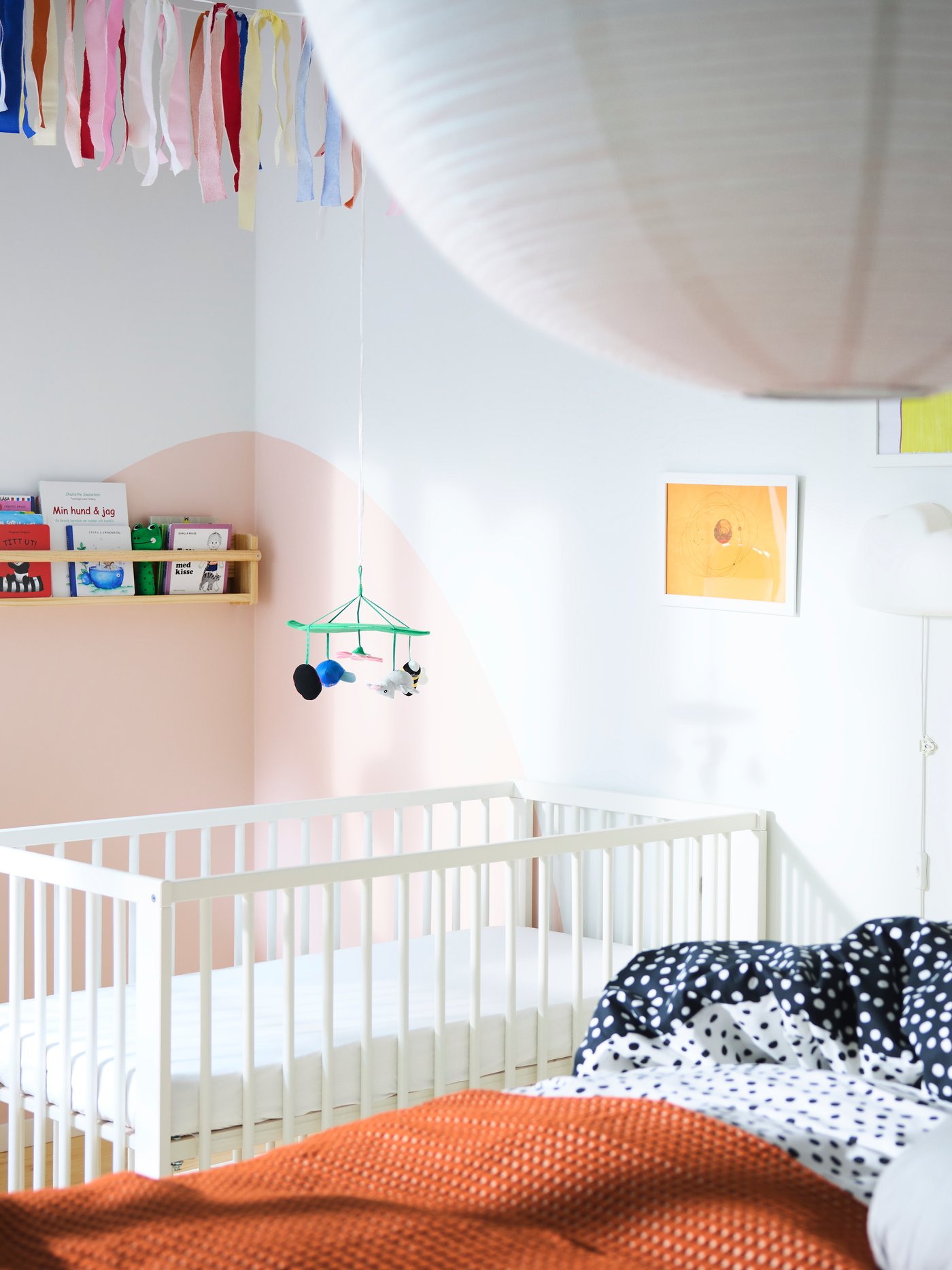 חדר שינה עם מיטה גדולה בחזית ומיטת תינוק ברקע, מדפים שונים עם ספרים וציורים רבים.