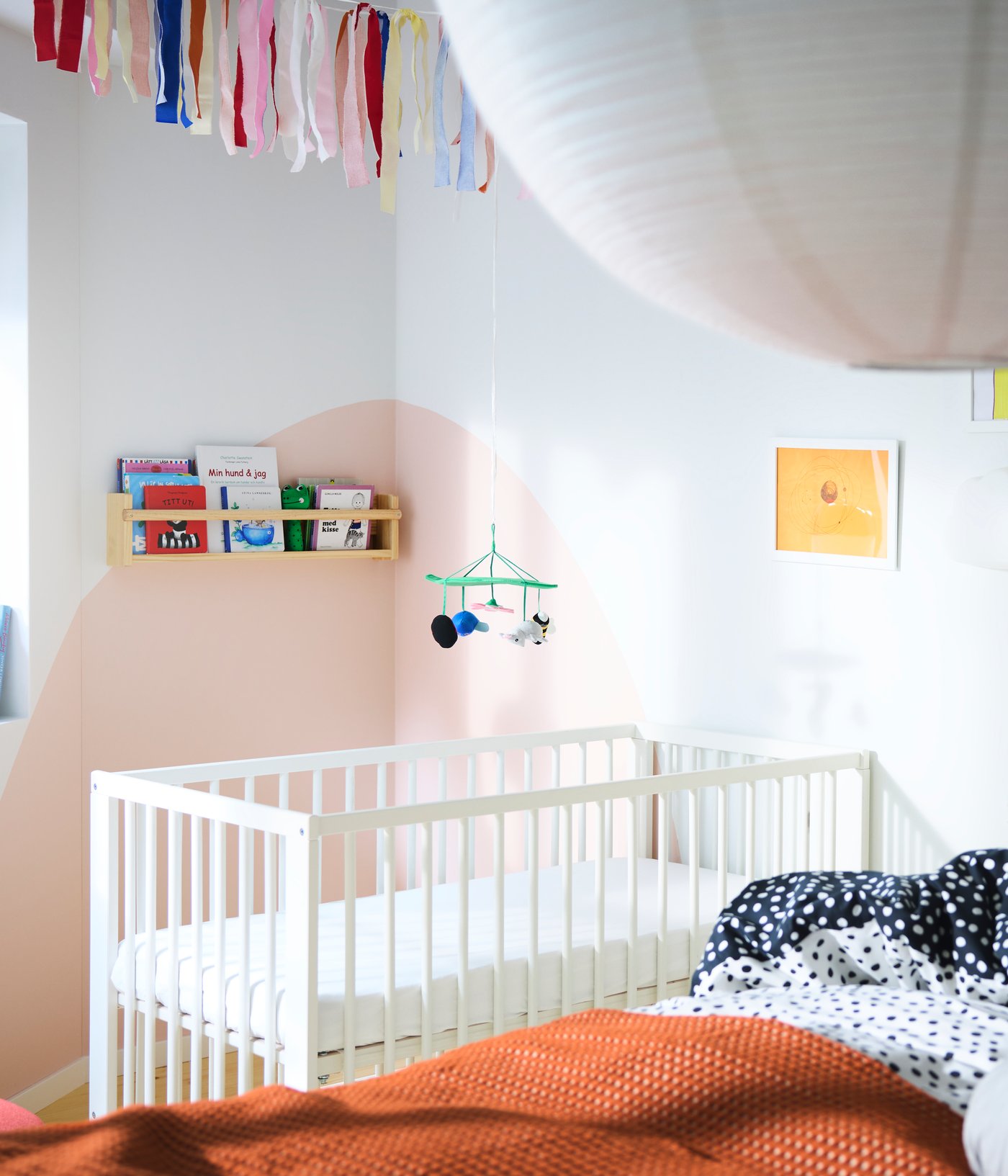 Una camera da letto con un grande letto in primo piano e un lettino sullo sfondo, diversi scaffali con libri e molti quadri.