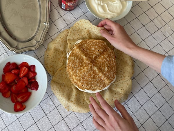 Närbild på en person som börjar vika ihop sista lagret av en pannkakstårta.